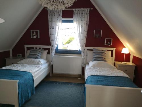2 Betten in einem Zimmer mit roten Wänden und einem Fenster in der Unterkunft Ferienhaus Seehund in Glowe