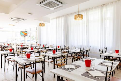 a dining room with tables and chairs and windows at Hotel Sorriso in Misano Adriatico