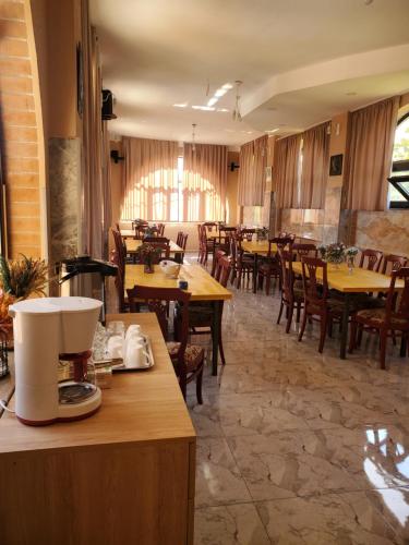 a restaurant with wooden tables and chairs and a kitchen at Gogi's Paradise Guesthouse in Akhmety
