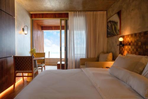 um quarto de hotel com uma cama e uma sala de estar em Duke Beach Hotel Maresias em Maresias