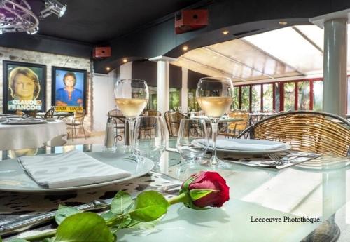 a table with glasses of wine and a rose on it at Gîte Le Carpe diem Milly-la-Forêt in Milly-la-Forêt