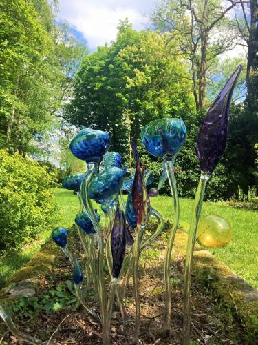 a group of glass flowers in a garden at Gîte Le Carpe diem Milly-la-Forêt in Milly-la-Forêt