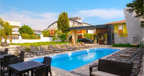 - une piscine avec des chaises longues et des tables à côté d'un bâtiment dans l'établissement Iberis Hotel Lara, à Altınkum