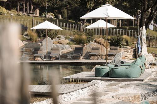 a pool of water with chairs and umbrellas at ASTER Boutique Hotel & Chalets in Fügenberg