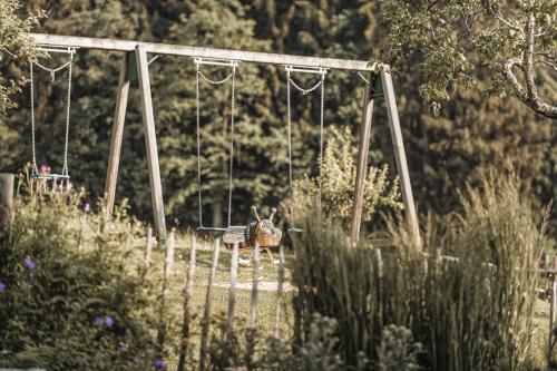 a chicken sitting on a swing in a garden at ASTER Boutique Hotel & Chalets in Fügenberg