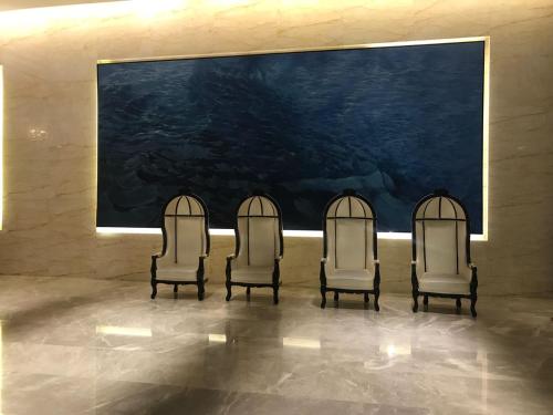 three chairs sitting in a room with a large painting at KLCC Sky Villa Suites Platinum in Kuala Lumpur
