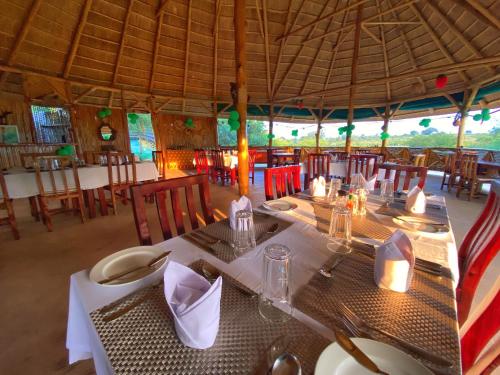 a dining room with a table and chairs in a restaurant at Murchison Falls Bamboo Village in Murchison Falls National Park