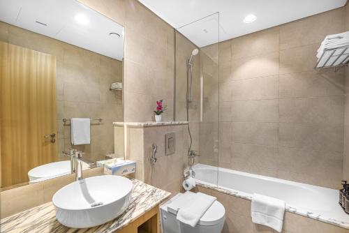 a bathroom with a sink and a tub and a toilet at Paramount Hotel Apartment Midtown - Platinium Dubai in Dubai