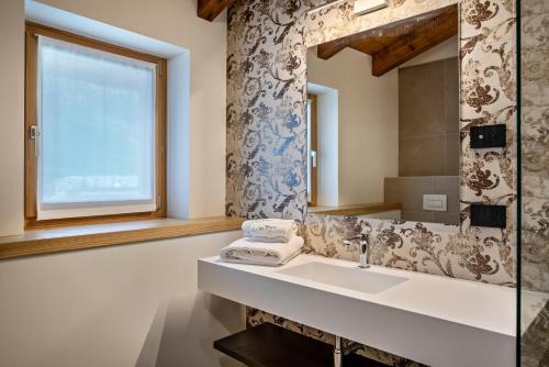 een badkamer met een wastafel en een spiegel bij Appartamento Midum Domus Attic in Trento
