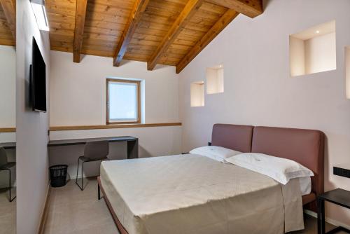 een slaapkamer met een bed, een bureau en een televisie bij Appartamento Midum Domus Attic in Trento