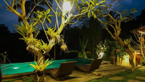 a pool in a garden at night with trees at Sebatu Tulen Villa in Tegalalang