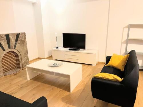 a living room with a tv and a couch and a table at Superbe appartement aéroport et gare Charleroi in Charleroi