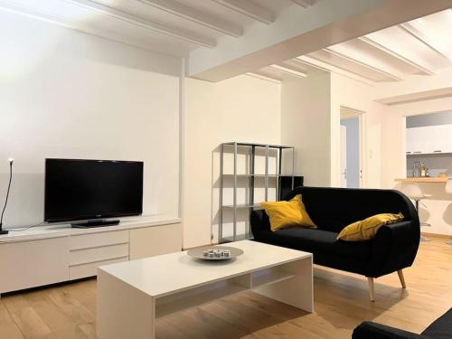 a living room with a black couch and a tv at Superbe appartement aéroport et gare Charleroi in Charleroi