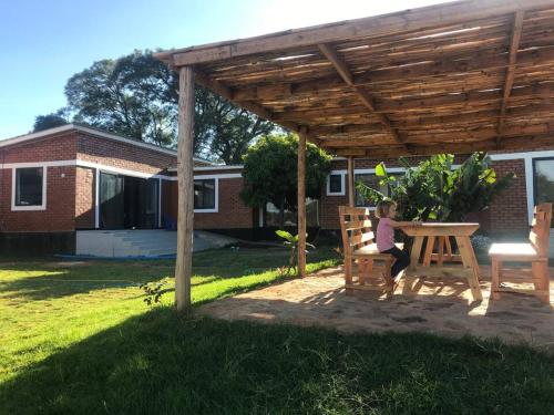 a girl sitting on a bench under a wooden pergola at Mountain View Town House in Iringa