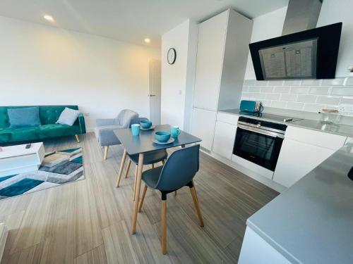 a kitchen and living room with a table and a couch at Leigh On Sea - Prime Location! Ultra Modern Entire Apartment With Free Gated Parking & Private Balcony in Southend-on-Sea