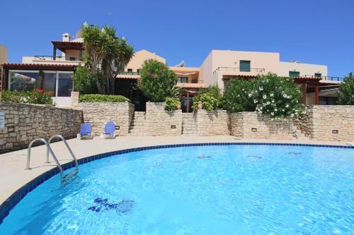una gran piscina con 2 sillas y una casa en Villa Oscania en Georgioupolis