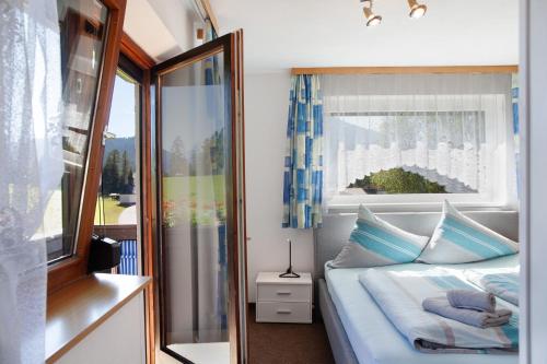 ein Schlafzimmer mit einem Bett mit blauen Kissen und einem Fenster in der Unterkunft Fewo 3 Haus am Lärchenhang in Leutasch