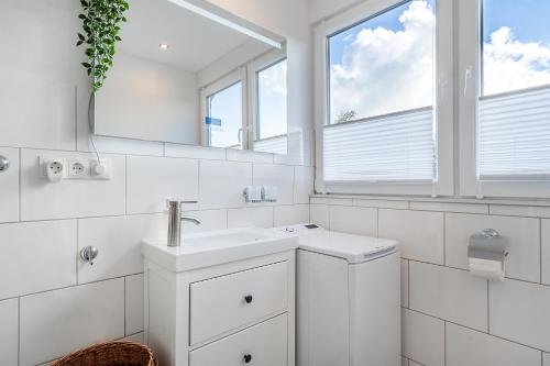 a white bathroom with a sink and a mirror at Haus am See, exquisites Relaxen in Südbrookmerland