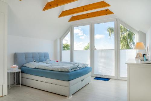 um quarto com uma cama azul num quarto com janelas em Haus am See, exquisites Relaxen em Südbrookmerland