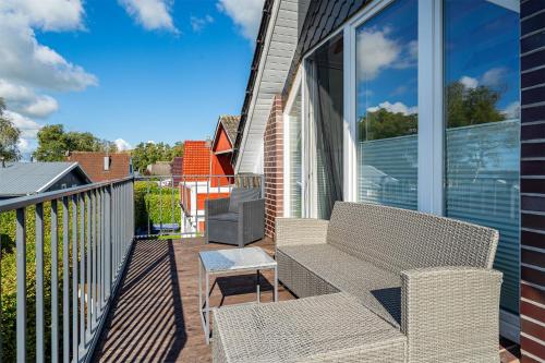 a balcony with a couch and a table and chairs at Haus am See, exquisites Relaxen in Südbrookmerland