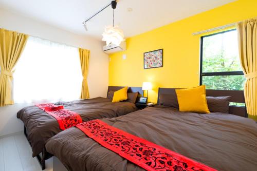 富士吉田市にあるMIYABI Highland Terrace Villa Bの黄色い壁の客室内のベッド2台