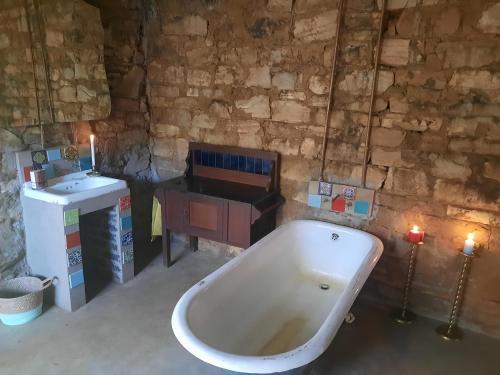 a bath tub in a room with a table and candles at Kwaggaskop Farm Kliphuis in Dullstroom