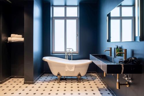 a blue bathroom with a tub and a sink at The Villa by Frogner House in Stavanger