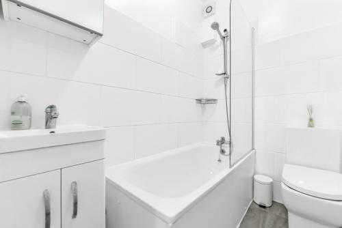a white bathroom with a shower and a toilet at Finsbury Park Station Apartment! (B) in London