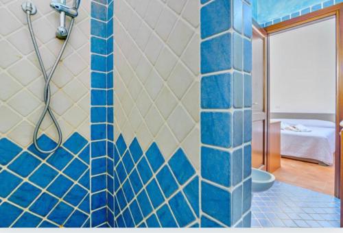 baño con ducha y pared de azulejos azules en Appartamento Le Palme Costa Smeralda en Arzachena