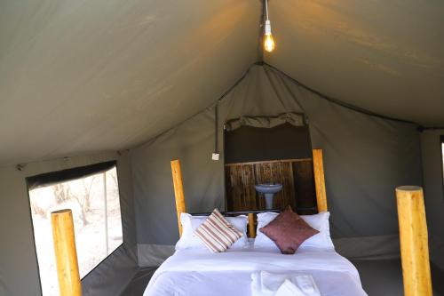 ein Schlafzimmer mit einem Bett in einem Zelt in der Unterkunft Emunyan Mara Camp in Narok