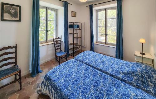 a bedroom with a blue bed and two windows at Amazing Home In Ouveillan With Outdoor Swimming Pool And 5 Bedrooms in Ouveillan