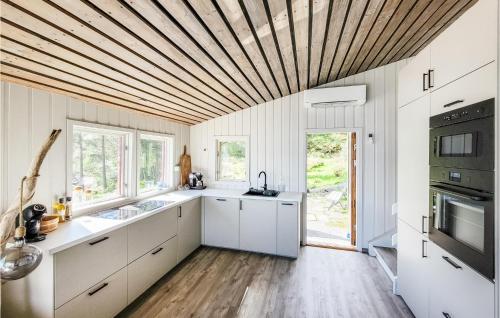 a kitchen with white cabinets and a wooden ceiling at Stunning Home In Trvikbygd With Kitchen in Tyrvikbygd