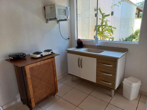 uma pequena cozinha com um lavatório e uma janela em CHALÉ do LÚ ILHABELA em Ilhabela