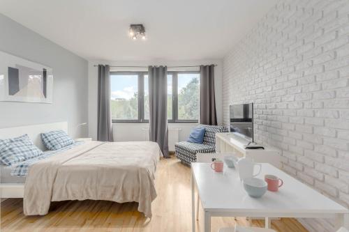 a white bedroom with a bed and a white brick wall at Chill Apartments Studio in Warsaw