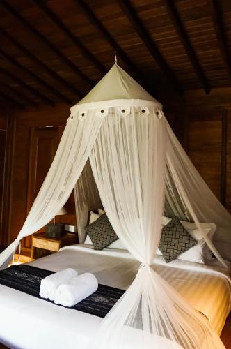 a canopy bed with white drapes on top of it at Sebatu Tulen Villa in Tegalalang
