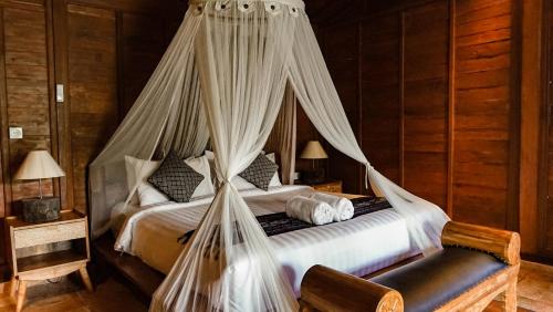 a bedroom with a bed with mosquito netting at Sebatu Tulen Villa in Tegalalang
