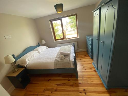1 dormitorio con cama, ventana y vestidor en Cosy 4 Bedroom Galway House with Rear Garden Patio en Galway