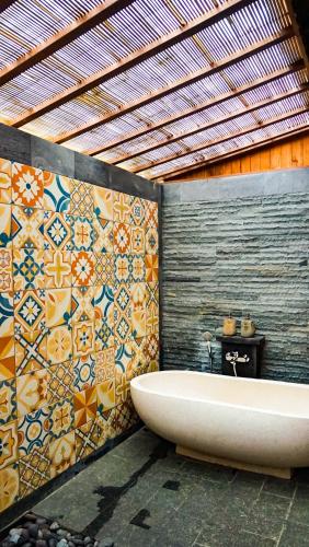 a bathroom with a tub and a tile wall at Sebatu Tulen Villa in Tegalalang