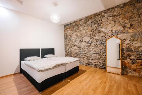 a bedroom with a stone wall and a bed at Michalska Residence 1 in Bratislava