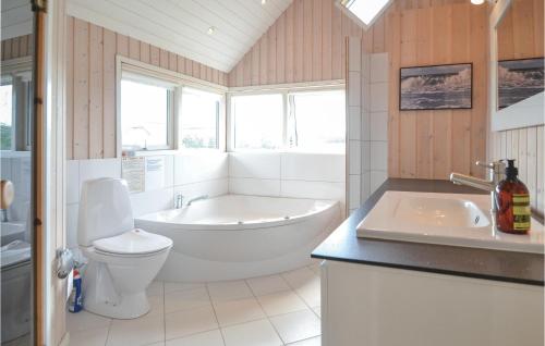 a bathroom with a tub and a toilet and a sink at Lyngbo in Havrvig