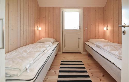 two beds in a room with a door and a window at Lyngbo in Havrvig