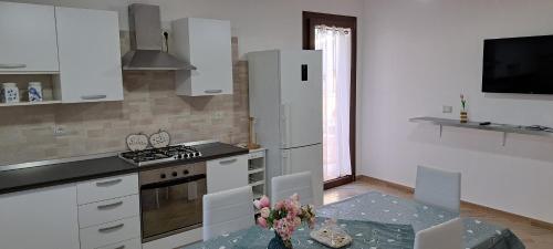 a kitchen with white cabinets and a table with flowers at Casa Terra Del Sole in Pula