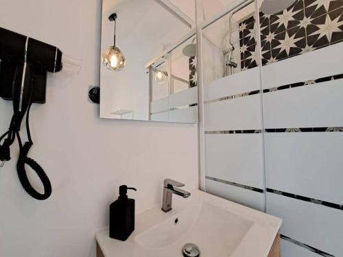 La salle de bains est pourvue d'un lavabo et d'un miroir. dans l'établissement Mascate - Appartement Climatisé en Hypercentre, à Reims