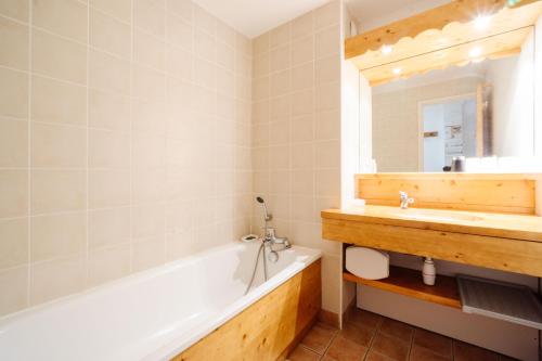 a bathroom with a tub and a sink and a mirror at le plein soleil méribel mottaret in Les Allues