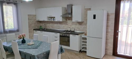 a kitchen with a table and a white refrigerator at Casa Terra Del Sole in Pula