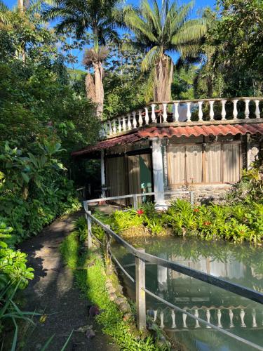 una pequeña casa con un estanque delante en Botanica Gardens and Eco Lodge, en San Gerardo