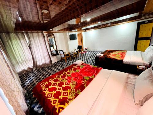 a room with two beds and a table with roses on it at Hotel Crown Pine Pahalgam in Anantnāg