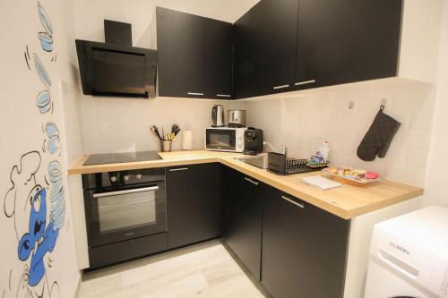 une petite cuisine avec des placards noirs et un four micro-ondes dans l'établissement la BD : joli T2 rénové /Wi-fi/centre-ville, à Angoulême
