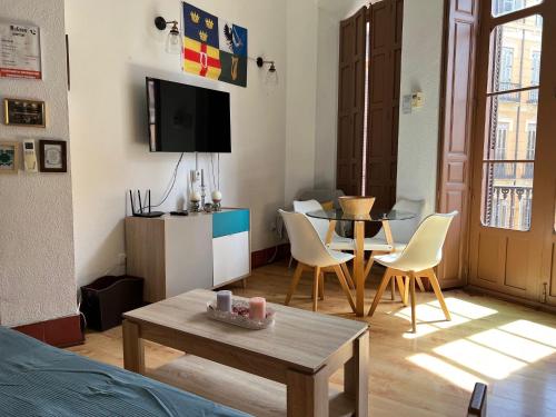sala de estar con TV, mesa y sillas en MacGregor Apartment, en Málaga