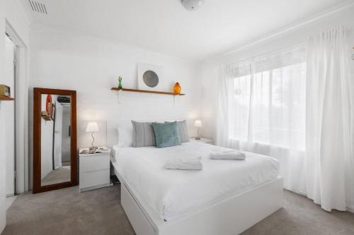 um quarto branco com uma grande cama branca e um espelho em Fitzroy North Boutique Bliss by Merri Creek Trail em Melbourne